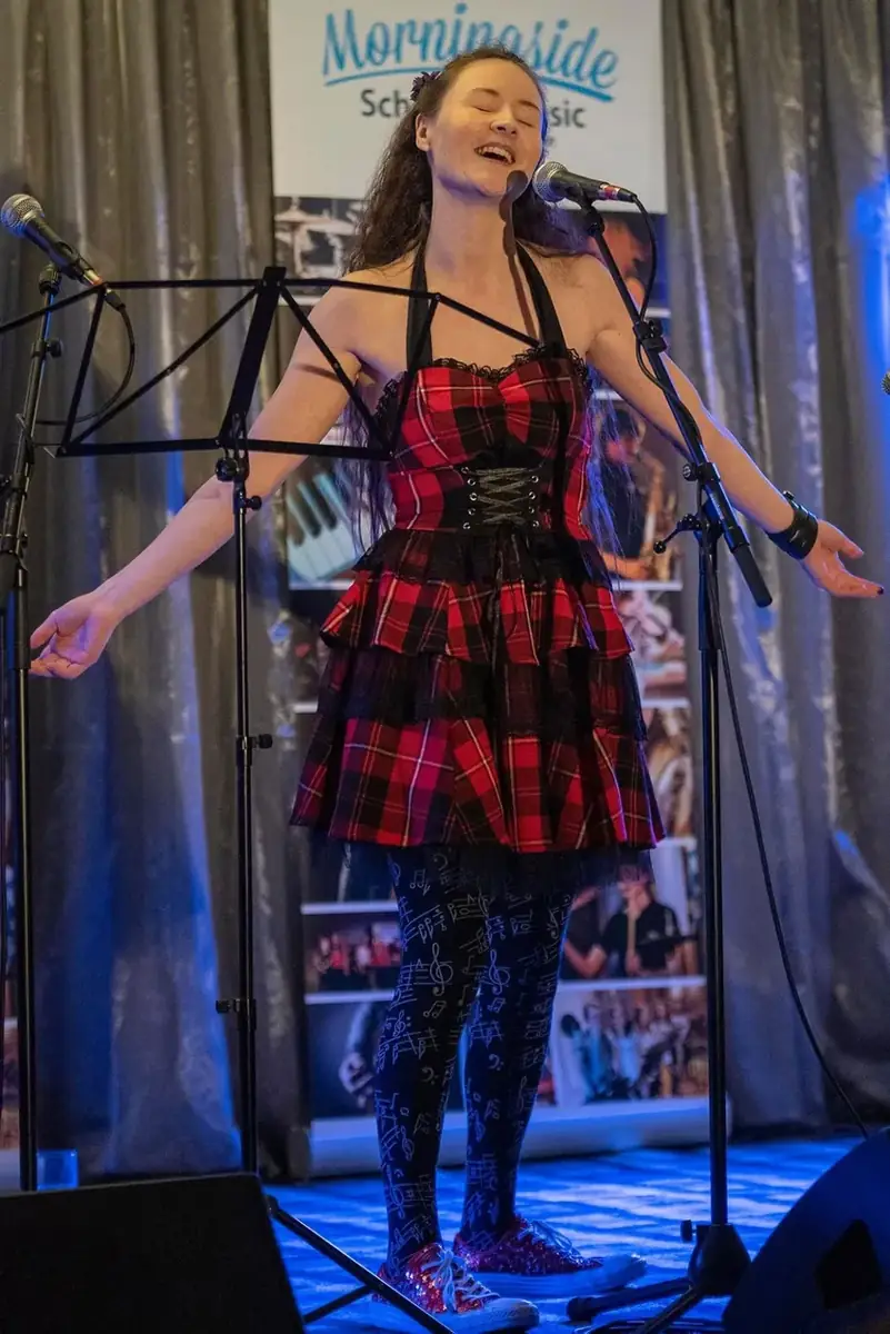 An adult student singing live at a Morningside School of Music showcase in Edinburgh