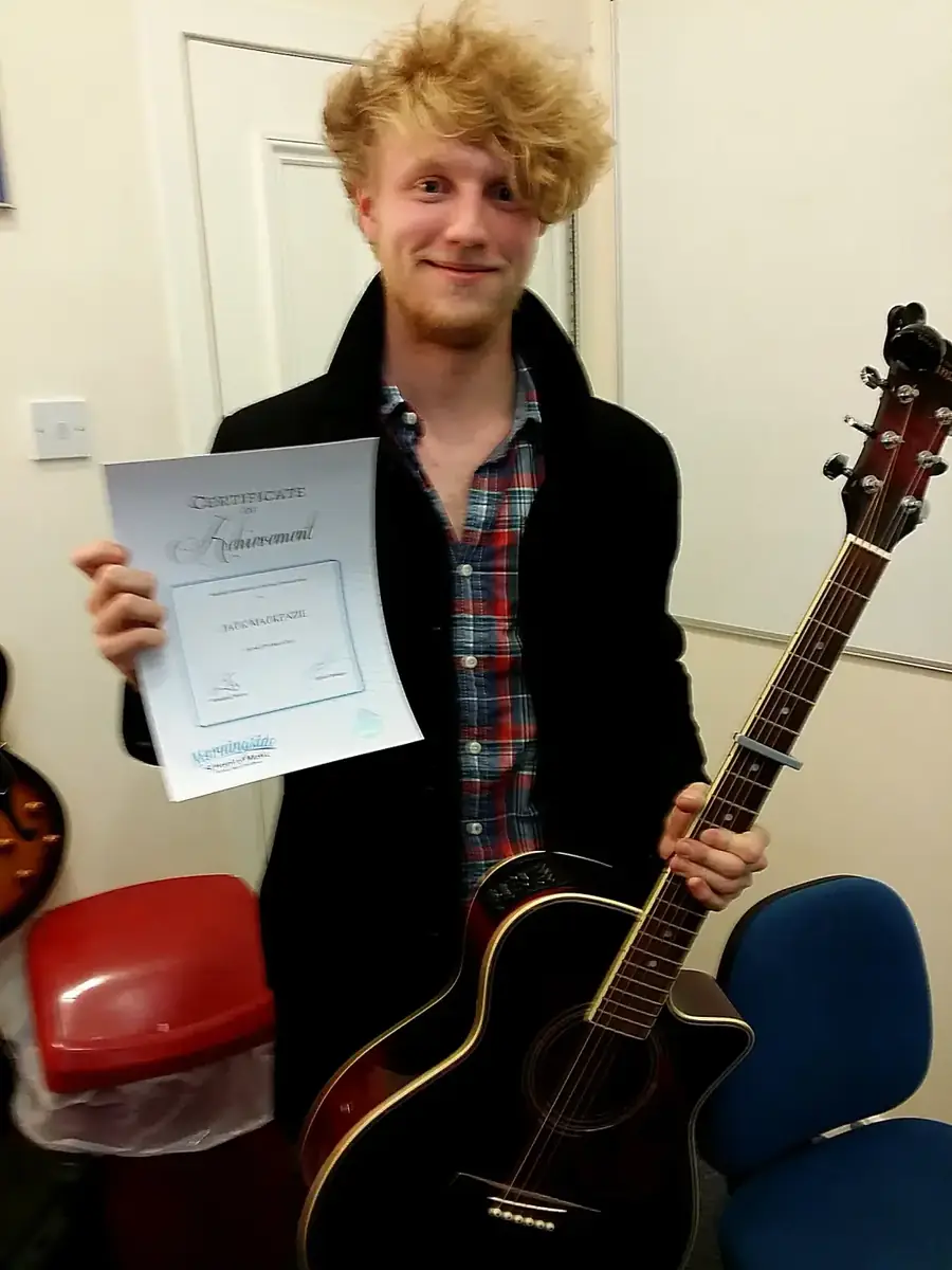 Guitar student Jack Mackenzie holding his certificate of achievement at Morningside School of Music