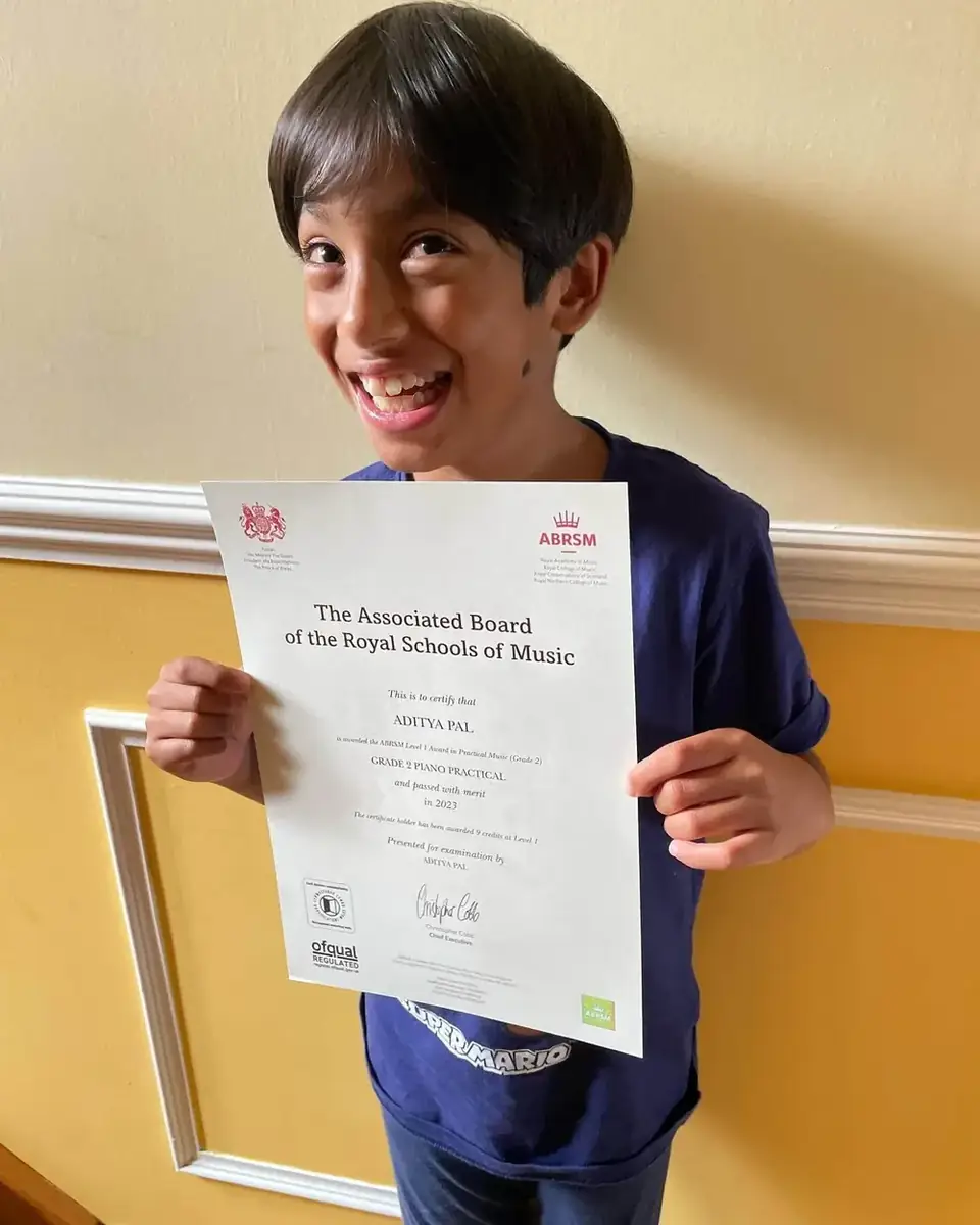 A young guitar student at Morningside School of Music with his exam certificate